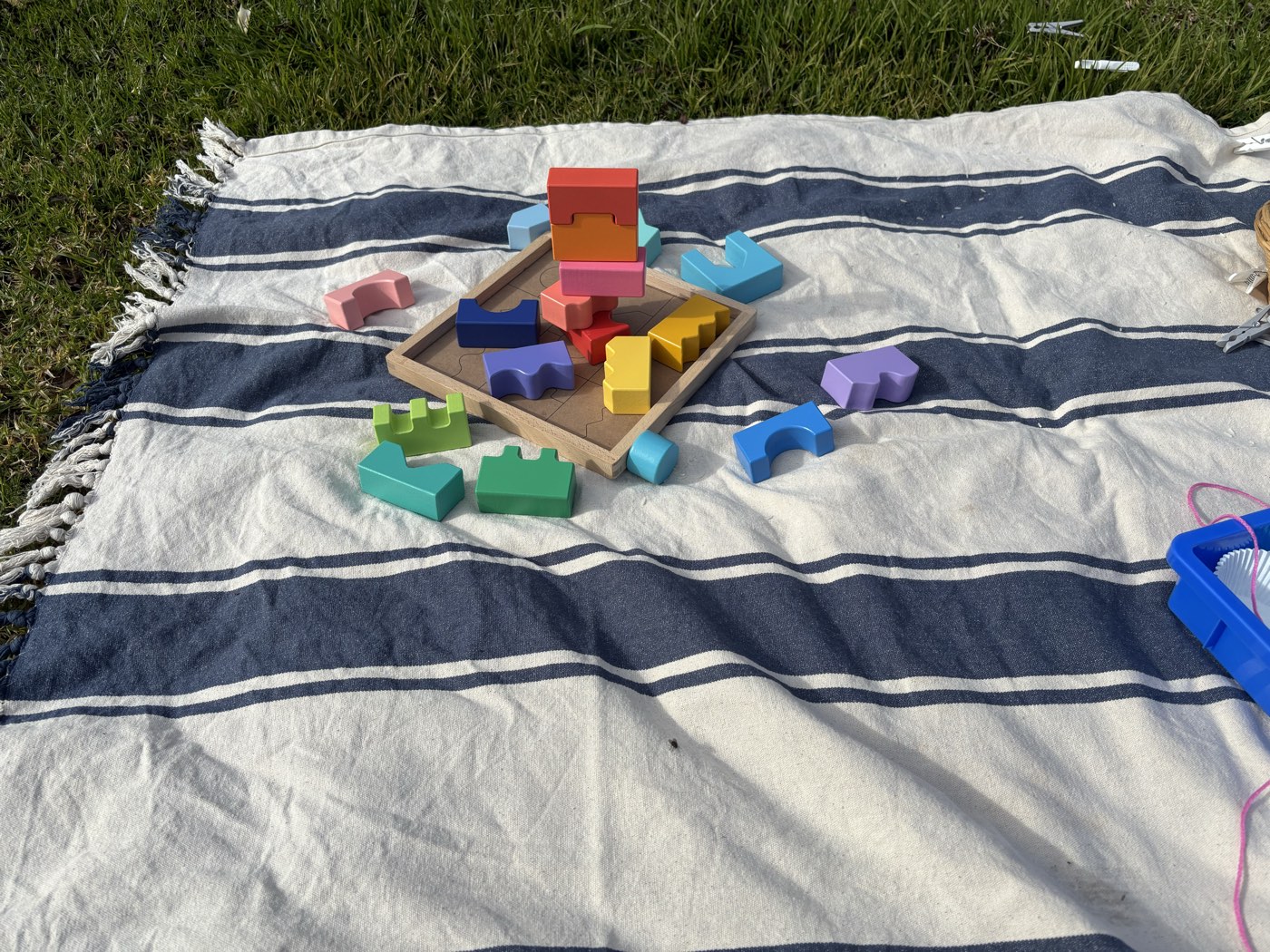 A tower of colourful wooden blocks built on a picnic rug