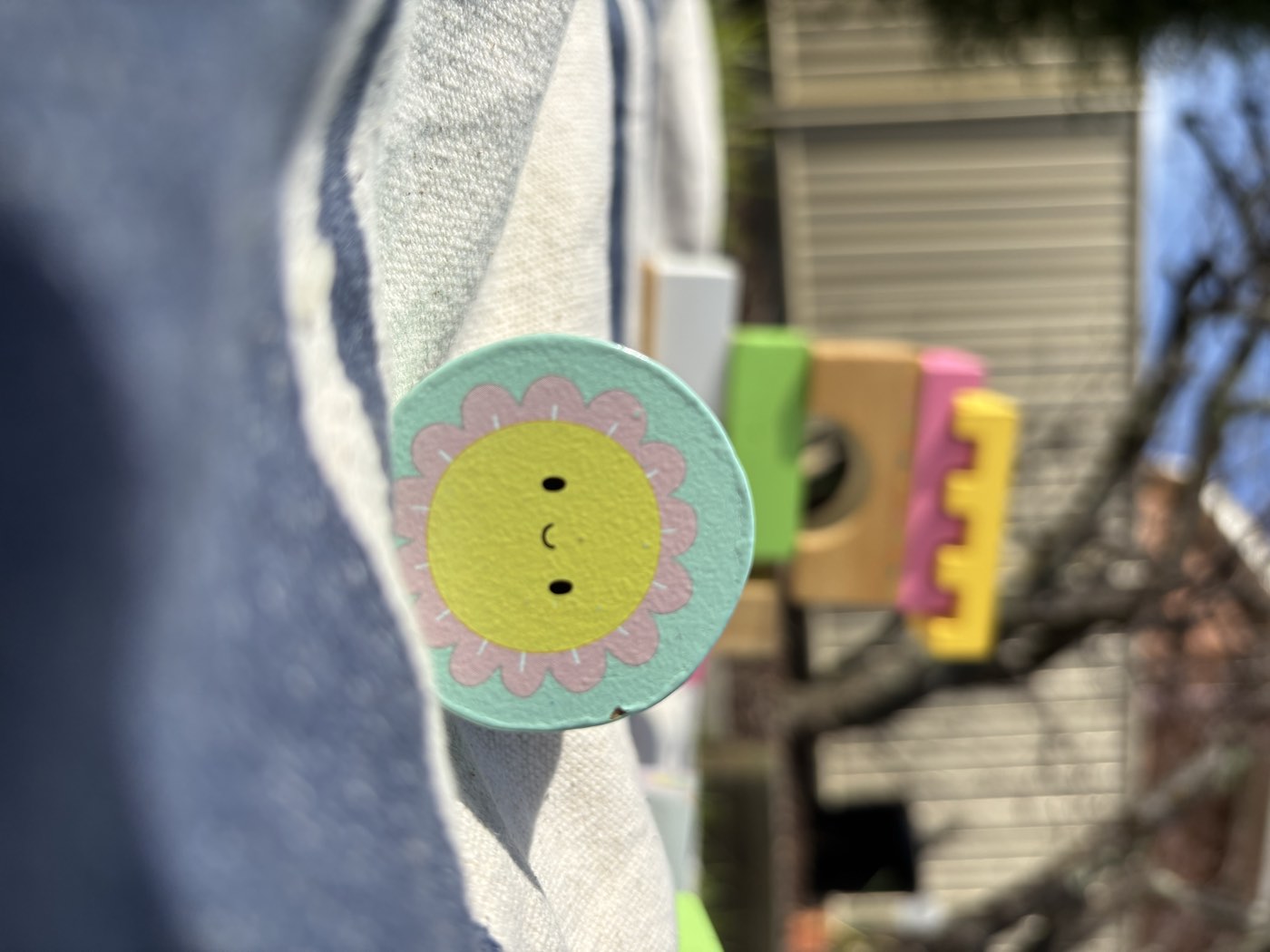 A smiling wooden flower toy standing on a picnic rug